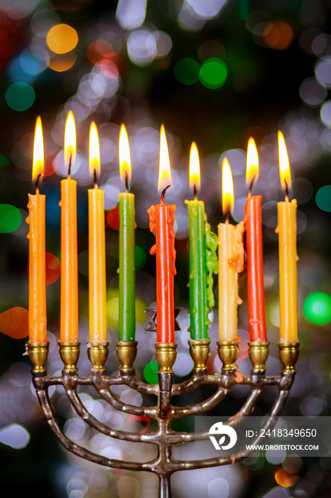 Hanukkah background with menorah and burning candles on sparkle background with defocused lights.