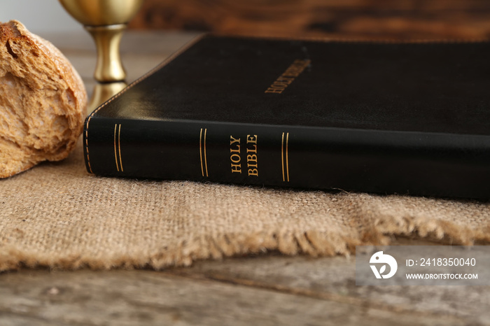 Holy Bible with bread on wooden table