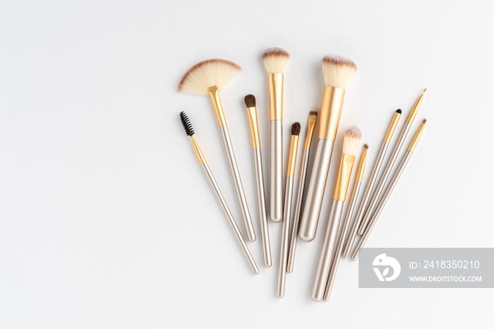 Golden makeup brushes set isolated on white background. Top view. Flat lay