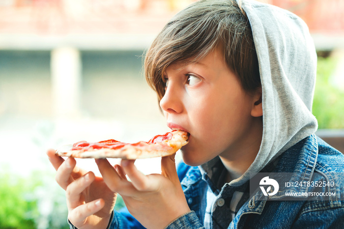 Hungry boy eating pizza. Schoolboy having lunch during break