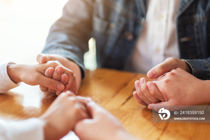 Group of people sitting in a circle holding hands and pray together or in therapy session