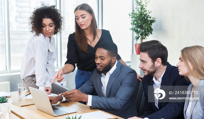 Business managers analyzing data on laptop at meeting