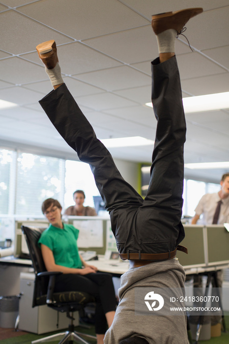 Businessman doing handstand in office