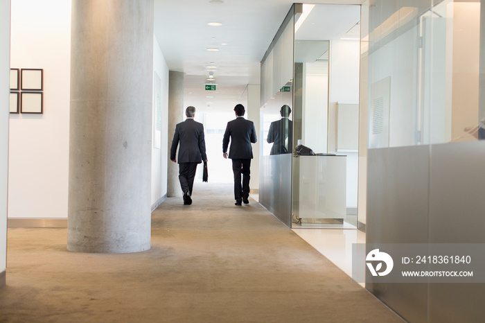 Corporate businessmen walking in modern corridor