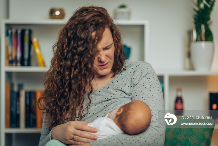 Mother in pain breastfeeding baby