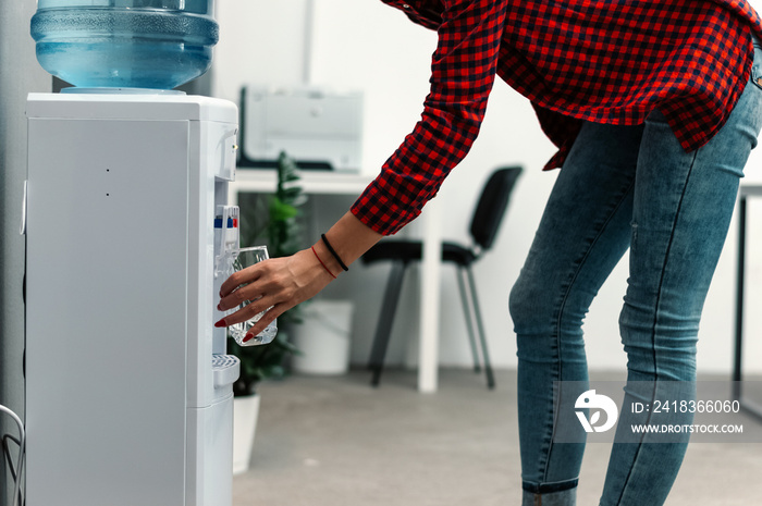 Young woman pouring water from machine into glass