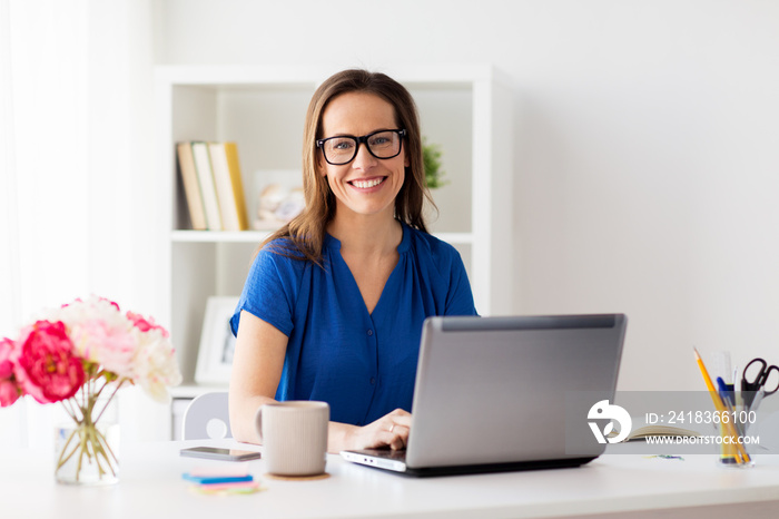 happy woman with laptop working at home or office