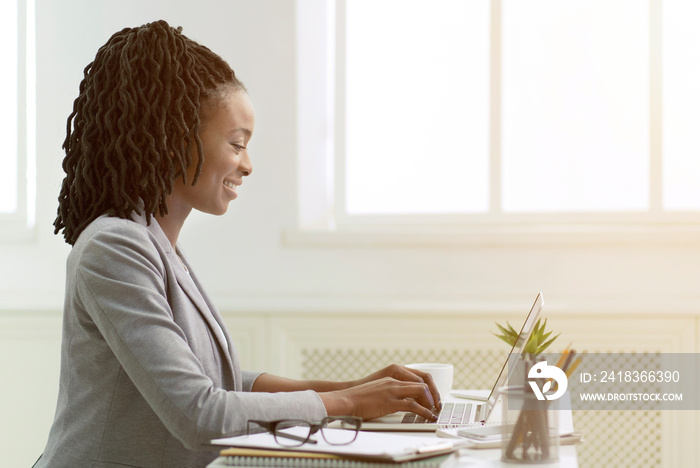 African American Woman Working On Laptop In Office, Side View