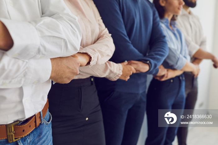 We are one team. Closeup of confident business partners standing in row holding hands