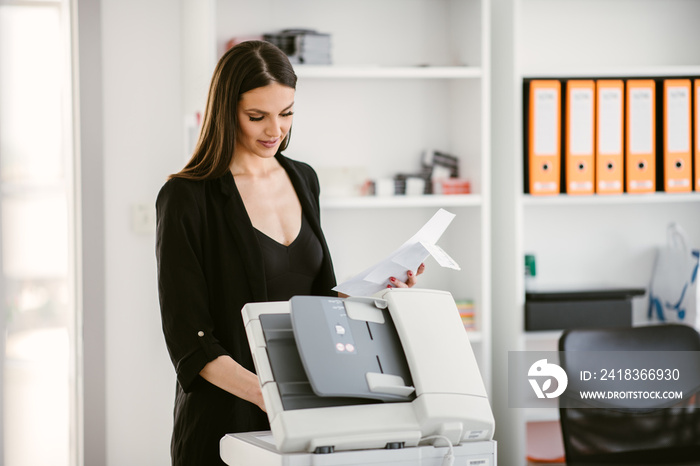 Female manager at the office. Employee working with the printer.