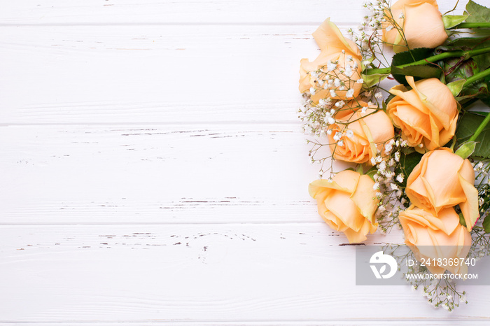 Border from peach color roses flowers on white wooden background.