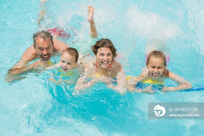 快乐的父母和孩子在泳池里玩得开心