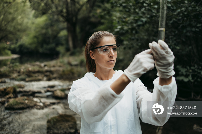 身穿防护服的女科学家、生物学家和研究员从被污染的河流中采集水样