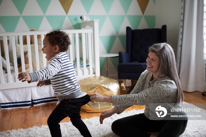 Side view of happy mother catching playful son running at home