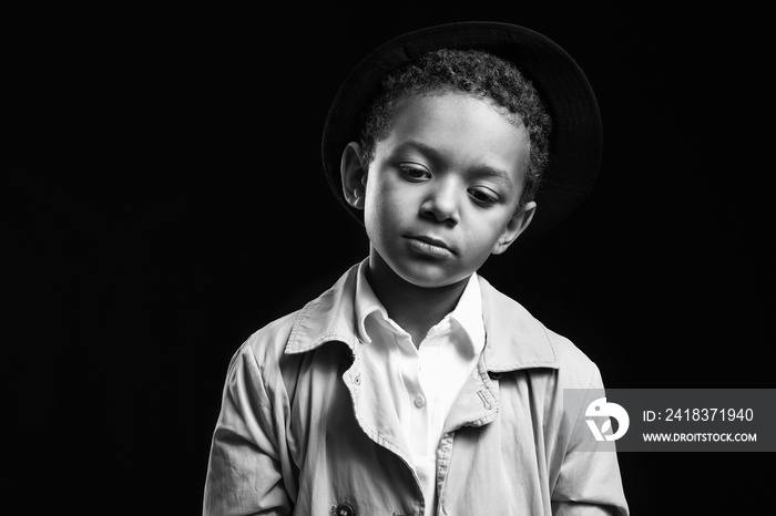 Black and white portrait of sad African-American boy on dark background