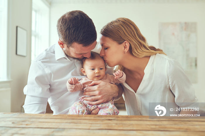 Mother kissing her little girl cradled in her husbands arms