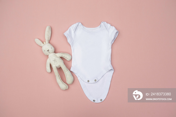 Blank white baby bodysuit/grow with cream rabbit soft toy on a pastel pink background - newborn clot