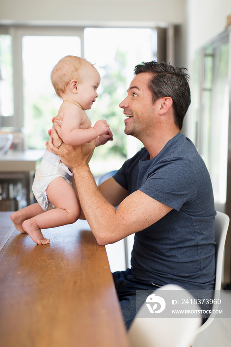 Happy father holding baby son at dining table