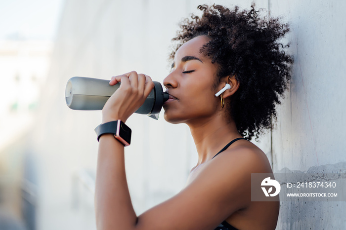 Athletic woman drinking water after work out outdoors.