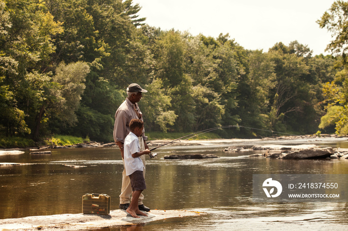 Boy and grandfather fishing in river