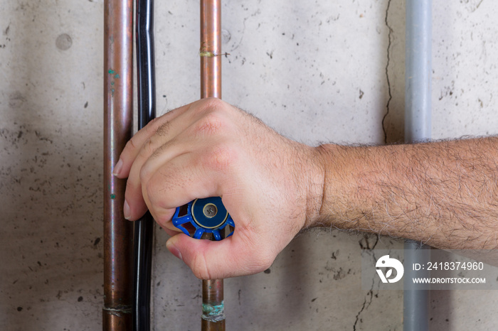 Man using strength to turn a water valve on a pipe