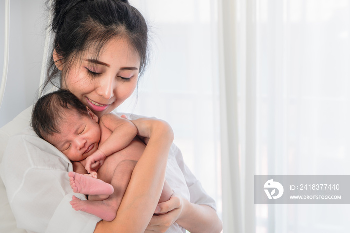 Asian mother holding her baby boy on hand with happiness