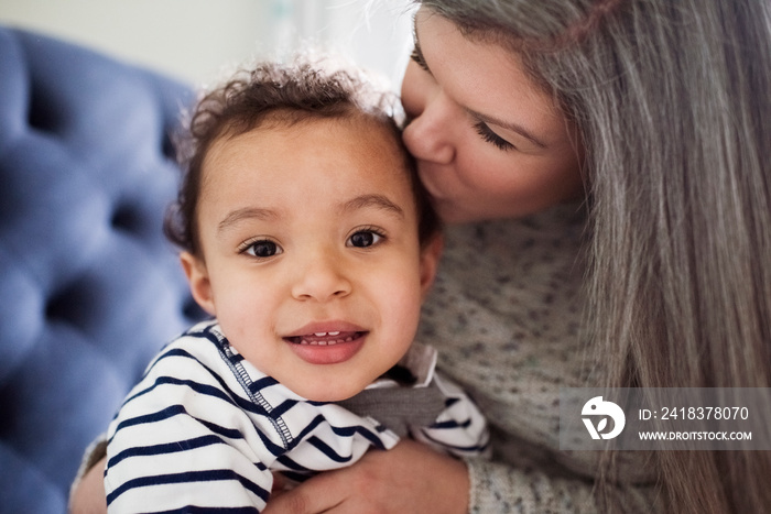 Close-up of loving mother kissing cute on son head while sitting at home