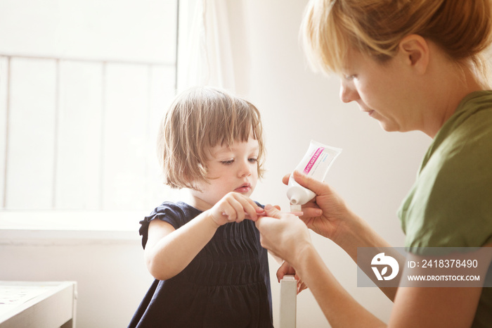 Mother applying toothpaste on daughters (2-5 months) toothbrush