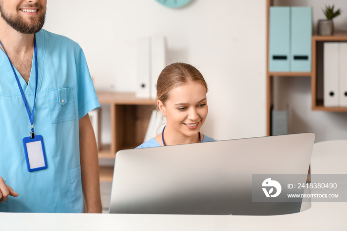 Male and female receptionists working at desk in clinic