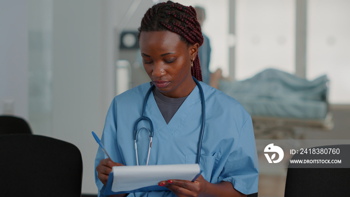 Close up of african american nurse looking at checkup files in waiting room at clinic. Medical assis