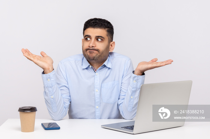 Dont know! Puzzled clueless confused businessman sitting office workplace with laptop on desk, shru