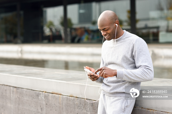 Attractive black man listening to music with headphones in urban