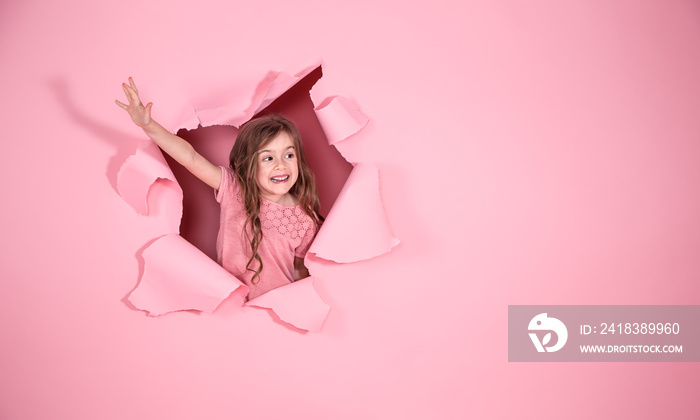 little girl playing superhero on pink background