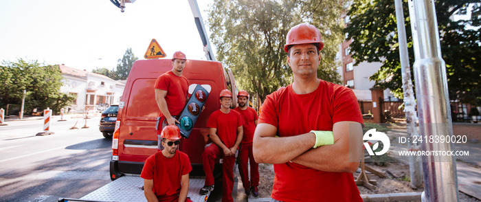 五名身穿红色工作服的建筑业高加索工人站在施工中的一辆起重车旁边