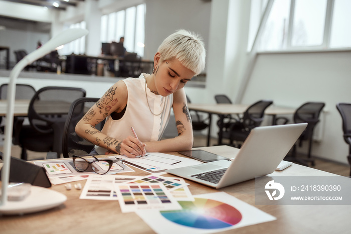 Creating something new. Young and beautiful creative female designer making a sketch while sitting a