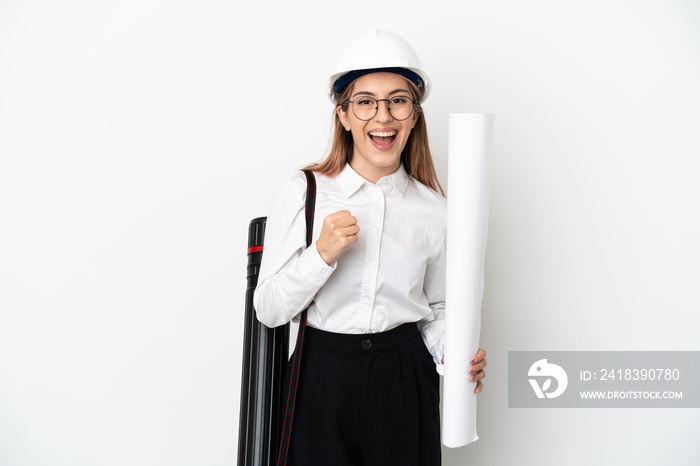 Young architect woman with helmet and holding blueprints isolated on white background celebrating a 