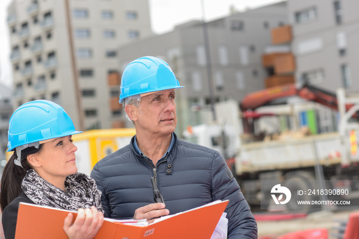 Construction manager and architect read their notes on a building site