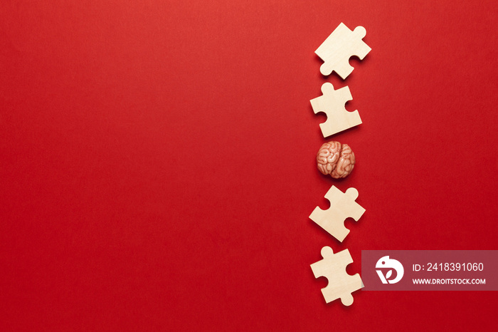 Human brain with a puzzle on red background. Business idea, memory loss, training and new skills.