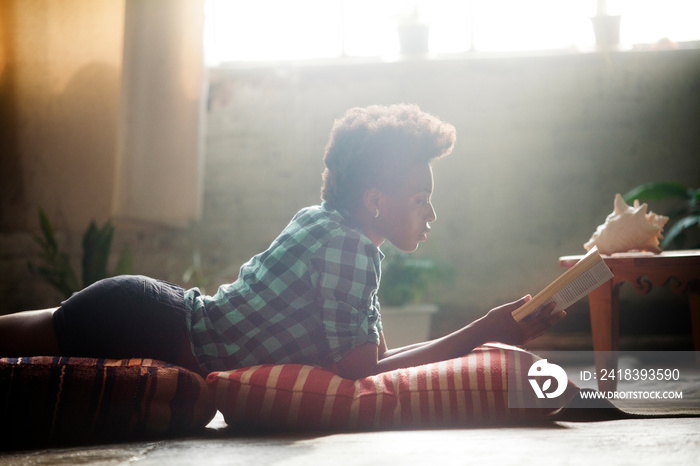 Young woman reading book in living room