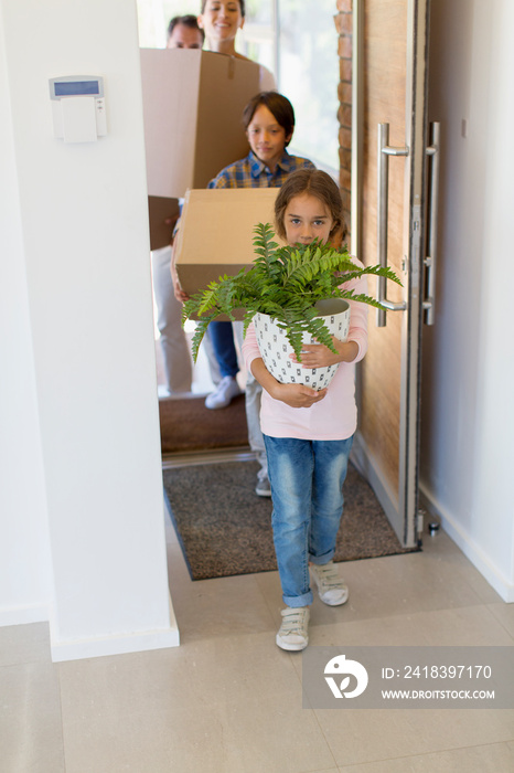 Girl carrying potted plant into new house