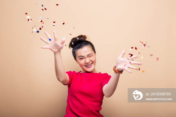 Portrait of a cheerful woman with confetti rain and celebrating isolated over background