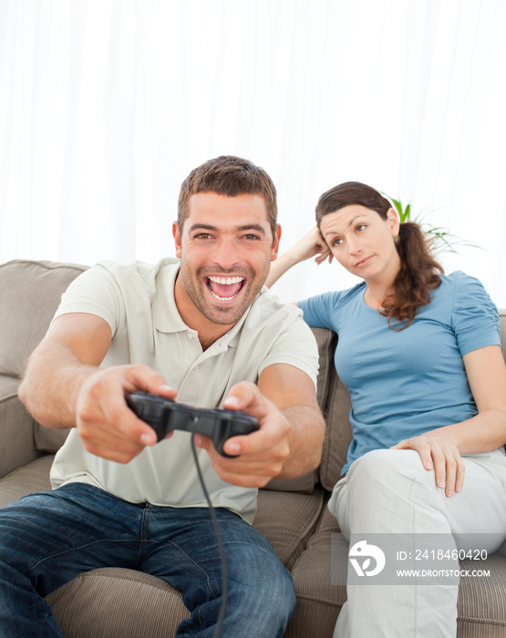 无聊的女人看着她的男朋友在玩电子游戏