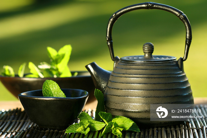 黑色铁制亚洲茶壶，上面有薄荷枝，用来泡茶