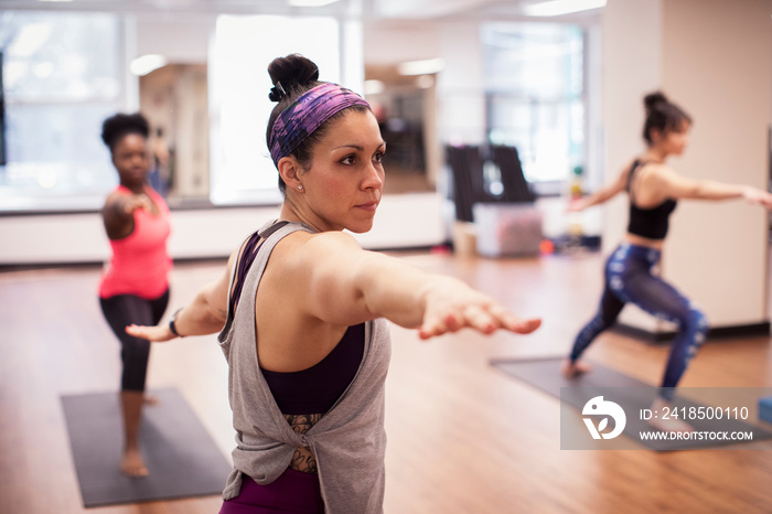 Female athletes practicing warrior 2 pose while standing in gym