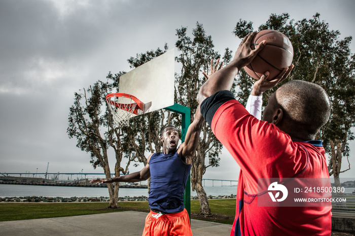 Young basketball players jumping to score hoop