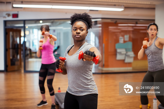 Confident female athletes exercising with dumbbells in gym