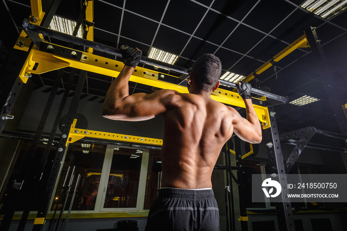 athletic african american man does pull-ups in gym on beam. power pull Up workout. how looks muscles