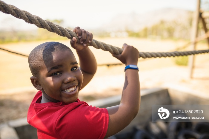 Portrait of happy boy crossing the rope during obstacle course