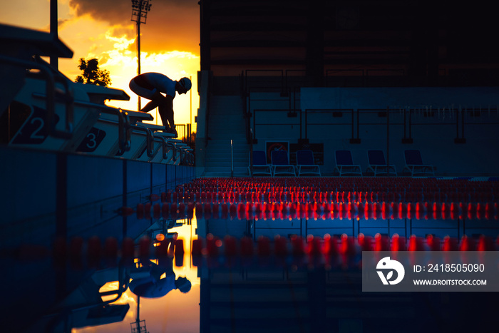 The swimmer jumps from the start block at the start of the race. Swimming sport concept photo. Black