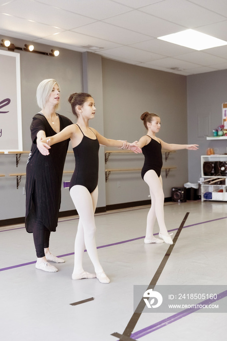 Instructor guiding students in practicing ballet at studio